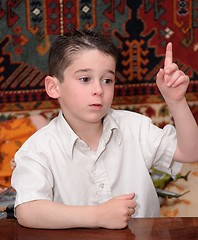 Image showing Serious cute little boy raises his finger