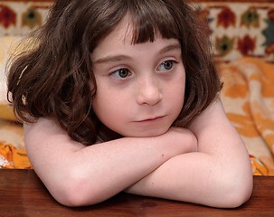 Image showing Serious cute little girl rests her head on crossed arms