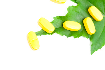 Image showing yellow vitamin pills over green leaf