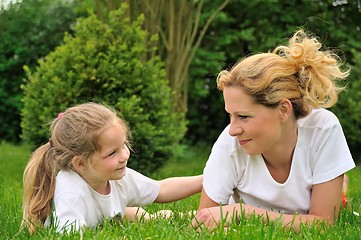 Image showing Young mother and daughter laying on the grass