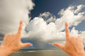 Image showing Hands Framing Dramatic Clouds over Tropical Shoreline