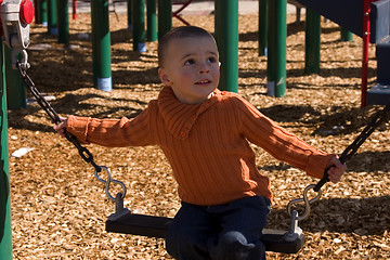 Image showing Child looking up while sitting on the swing