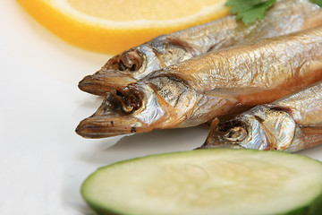 Image showing Smoked fishes with lemon, cucumber and green parsley.