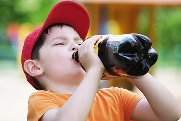 Image showing Little boy drinks from big bottle