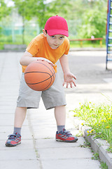 Image showing Little boy dribbling basketball
