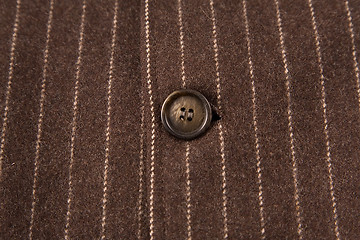 Image showing classic striped fabric with close-up of brown button 