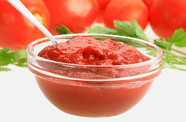 Image showing Ketchup in glass dish on background of red tomatos