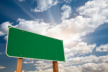 Image showing Blank Green Road Sign Over Clouds and Sunburst