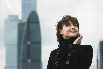 Image showing Smiling woman in black on cellphone