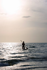 Image showing woman paddleboarding towards sun