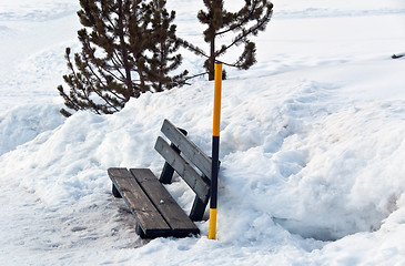 Image showing Snow covered bench and snow pole