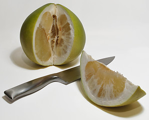 Image showing Pummelo with cut out slice and knife on white