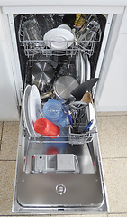 Image showing Dishwasher with open hatch and clean dinnerware