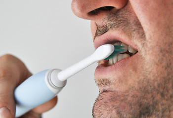 Image showing Man brushing his teeth with electric toothbrush