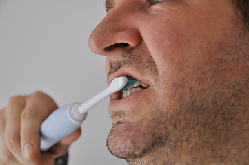 Image showing Man brushing his teeth with electric toothbrush