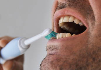 Image showing Man brushing his teeth with electric toothbrush