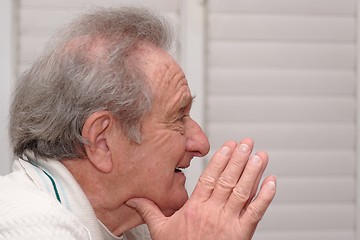 Image showing Smiling elderly man resting his head on hands