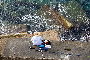 Image showing Fisherman is fishing on the sea stone, top horizontal view 