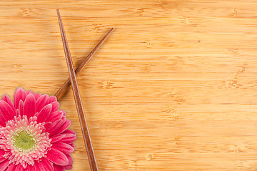 Image showing Gerber Daisy and Chopsticks on a Bamboo Background