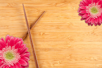 Image showing Gerber Daisy and Chopsticks on a Bamboo Background