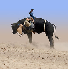 Image showing A cowboy falling off a bucking bull