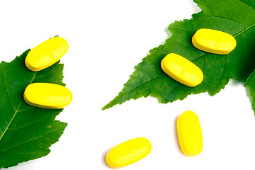 Image showing yellow vitamin pills over green leaves