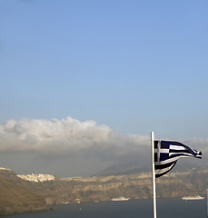 Image showing flag of Greece flying over the caldera Oia Santorini