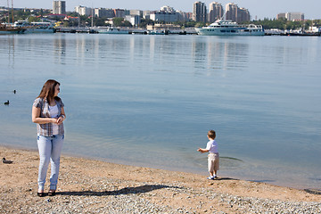 Image showing Girl looks like a little boy on the shore throwing pebbles into the sea