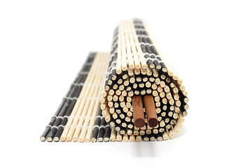 Image showing Rolled bamboo mat with chopsticks isolated on white