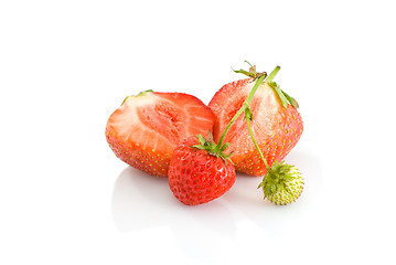 Image showing One green, unripe and pair of ripe red strawberries, with one cutted on half