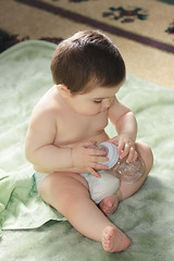 Image showing Baby sitting with bottle