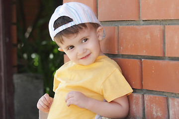 Image showing Little boy in yellow shirt at brick wall