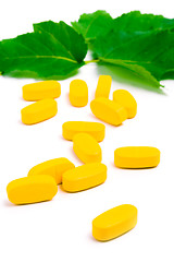 Image showing yellow vitamin pills over green leaves