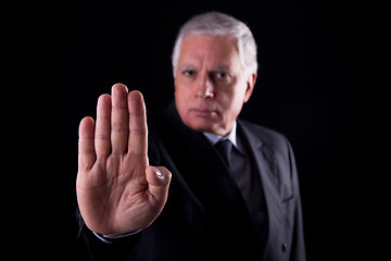 Image showing old businessman  with his hand raised in signal to stop