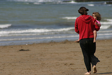 Image showing Mother carrying child on windy beach