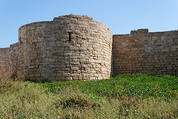 Image showing Round tower and wall of medieval castle among grass