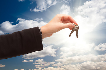 Image showing Female Holding Out Pair of Keys Over Clouds and Sky