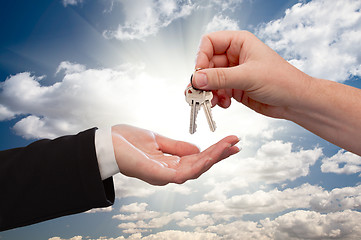 Image showing Male Handing Keys to Female Over Clouds and Rays