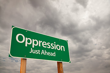 Image showing Oppression Green Road Sign Over Storm Clouds