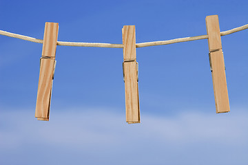 Image showing clothesline and pegs on blue sky background