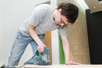 Image showing worker cutting floor board with jigsaw 