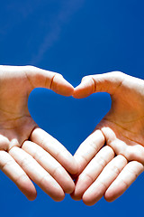 Image showing Heart combined from hands on blue background 