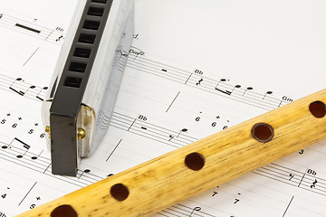 Image showing Harmonica and wooden pipe lying on notesheet