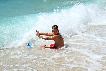 Image showing small boy sitting and stopping waves on sea