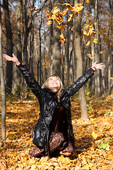 Image showing beautiful girl throwing up autumn leaves