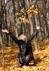 Image showing beautiful girl throwing up autumn leaves