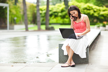 Image showing Woman on the phone and working on her laptop