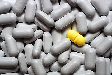 Image showing one yellow pill on gray pills