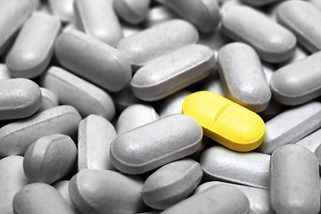 Image showing one yellow pill on gray pills