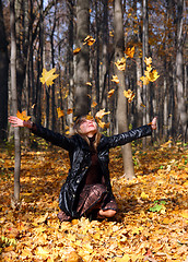 Image showing beautiful girl throwing up autumn leaves